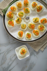 Gefüllte teuflische russische Eier mit Dill und orange Keta Lachs und gelb Saibling Kaviar auf Eierteller, Serviette grün, Silber Teller und Marmor Hintergrund hell