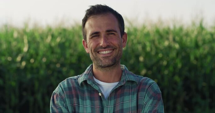 Portrait of a Happy Man Posing in a Green Field Full of Corn Crops and Smiling. Handsome Middle aged Male Farmer Looking at the Camera, Enjoying his Profession and Lifestyle in the Countryside 