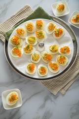 Gefüllte teuflische russische Eier mit Dill und orange Keta Lachs und gelb Saibling Kaviar auf Eierteller, Serviette grün, Silber Teller und Marmor Hintergrund hell