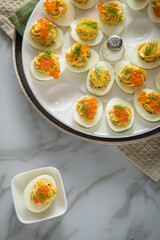 Gefüllte teuflische russische Eier mit Dill und orange Keta Lachs und gelb Saibling Kaviar auf Eierteller, Serviette grün, Silber Teller und Marmor Hintergrund hell