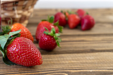Strawberry in basket and on table on wooden background
