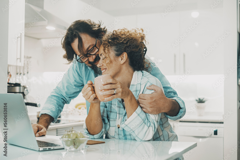 Wall mural man hugging woman at home in the kitchen with love. indoor leisure activity and relationship lifesty