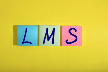 Learning management system. Colorful sticky notes with abbreviation LMS on yellow background, top...