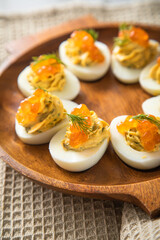 Gefüllte teuflische russische Eier mit Dill und orange Keta Lachs Kaviar auf Holz Eierteller und Serviette 