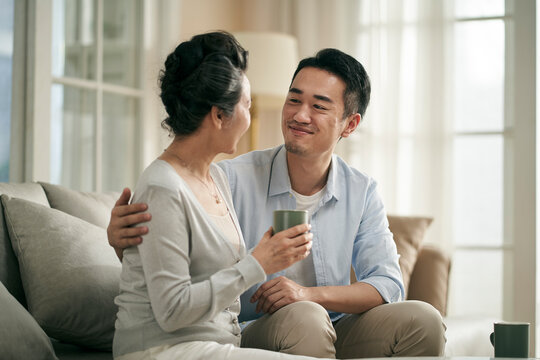 asian adult son chatting with senior mother at home