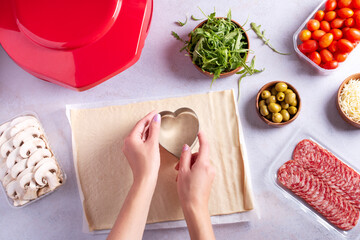 Making of mini pizzas in a heart shape for Valentines day holiday.