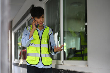 Engineer man in yellow vests having phone conversation while working in building construction site