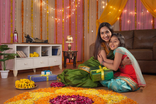 Beautiful little girl sitting with her mother near rangoli and enjoying Diwali preparation - Festival Concept. Image of a beautiful mother daughter enjoying the diwali festival wearing traditional ...