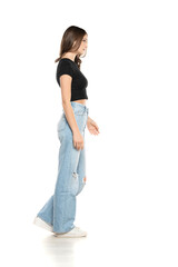 Young female model wearing ripped jeans and black shirt walking on a white background. Side, profilet view