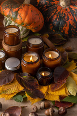 Soy candles burn in glass jars. Tree leaves, pumpkin. Comfort at home. Candle in a brown jar. Scent and light. Scented handmade candle. Aroma therapy. Autumn mood. Cozy home decor in fall.