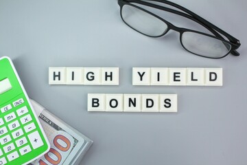 calculator, glasses and paper money with the alphabet word High-Yield Bonds.