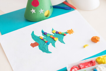 Making handmade Christmas cards. Childrens DIY concept. Little girl doing Christmas tree decoration or greeting cards from plasticine. Crafts for children.