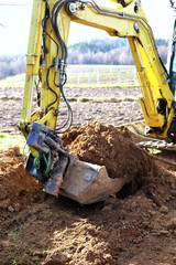 A small excavator at work on a construction site - obrazy, fototapety, plakaty