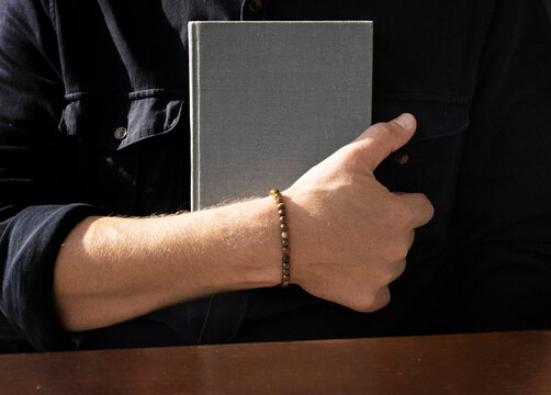 Man holding book with two arms, with copy space on light grey background. High quality photo