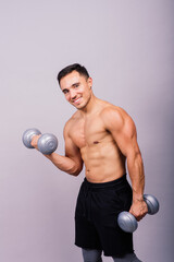 Fototapeta na wymiar Shirtless bodybuilder showing his great body and holding dumbell.