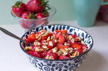 Strawberry salad with walnuts and poppy seeds in a black and white plate
