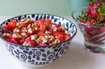 Strawberry salad with walnuts and poppy seeds in a black and white plate