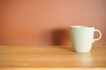 Green Ceramic coffee mug on wood table with brown background