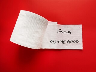 Toilet paper on red background with handwriting FOCUS ON THE GOOD, concept of remind self to keep...