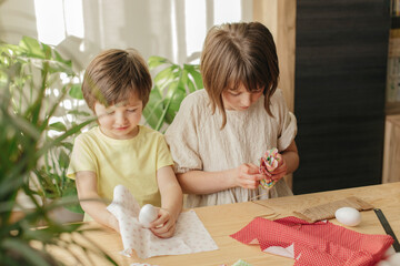 A boy and a girl, sibling are crafting Easter eggs from cloth in the shape of a bunny. Family preparations for Easter