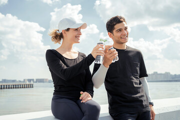 Drinking water from a plastic bottle, young men and women runners, happy runners. 