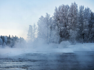 Obraz na płótnie Canvas Strong frost in January on the Shuya River in the Republic of Karelia, northwestern Russia. Steam over water. The waterfall in the river is partially frozen.