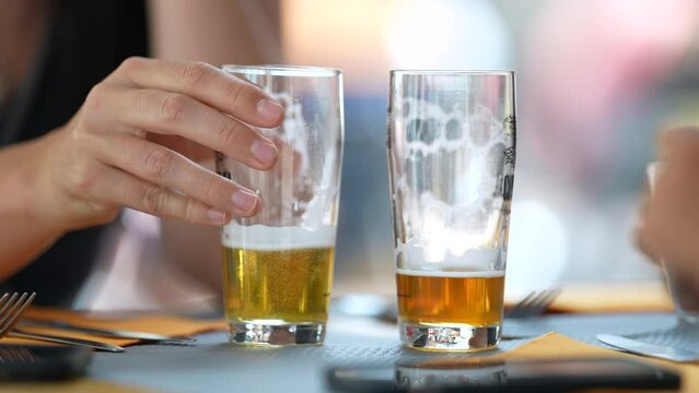 Two half full draft beers at restaurant table. Person hand closeup putting drink down