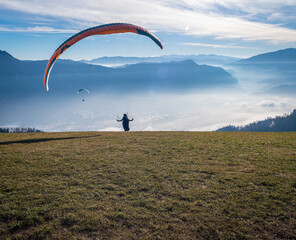 Man on a grassy slope prepare the glider for paragliding from Vetriolo Terme, Trento province - Trentino Alto Adige - Paragliding school - Italy