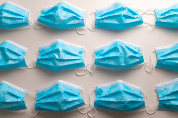 Blue surgical masks, arranged on white surface. Epidemic of covid and protection tools. 
