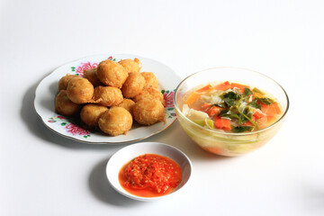 Indonesian food : Perkedel is fried patties (made of ground potatoes and minced meat), served with vegetable soup in clear bowl and chili sauce, isolated on white background