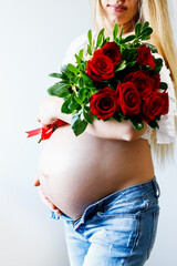 Eighth month of pregnancy. Close-up of beautiful pregnant girl with flowers. A series of photos of a pregnant girl. Pregnancy, parenthood and expectation concept.