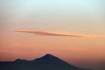Stunning sunset with beautiful shades of orange, pink, purple and blue colors with the silhouette of a mountain range. Wallpaper, natural background with copy space.