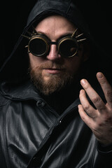 A man in a hood, wearing vintage steampunk goggles looking at the camera close-up