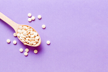 Heap of white pills on colored background. Tablets scattered on a table. Pile of red soft gelatin capsule. Vitamins and dietary supplements concept