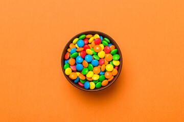 Multicolored candies in a bowl on a colored background. birthday and holiday concept. Top view with copy space