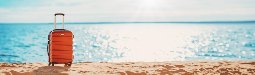 Panoramic view of the seacoast with suitcase on the sandbeach.