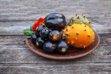 Organic orange kiwano melon with prickly thorns and black cherry tomatoes