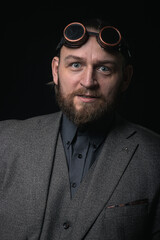 charismatic man in a classic suit and steampunk goggles on a black background stylish Portrait