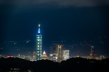 Fototapeta na wymiar Clouds moving in the sky at night. Neon lights shine on the vibrant cityscape. Hazy and dreamy night view of the city. Taipei City, Taiwan