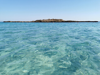 Obraz premium Fig Tree Bay beach, crystal clear water, white sand at the bottom, small island off the coast.
