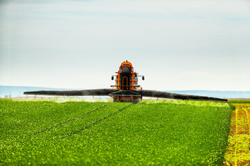 Tractor-applied herbicides, pesticides, and fungicides in wheat fields, farmer protecting crops...