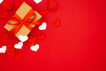 A gift in kraft box with a red bow on a red background with hearts. Valentine's day. Copy space. The concept of holidays and love