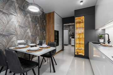 Modern cuisine in black in the dining table and kitchen appliances