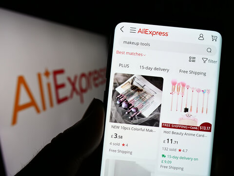 Stuttgart, Germany - 01-07-2023: Person holding cellphone with webpage of Chinese c-commerce company AliExpress on screen in front of logo. Focus on center of phone display.