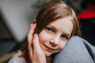 Close-up portrait of the face of a beautiful red-haired girl, a child, a daughter and a caring loving father. Photography, family.