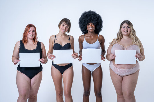 Multiracial group of women holding blank white board over belly, body positive concept, copy space on empty signs to write what you want