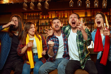 Emotional young people, friends meeting at pub to watch online game translation and drink beer....