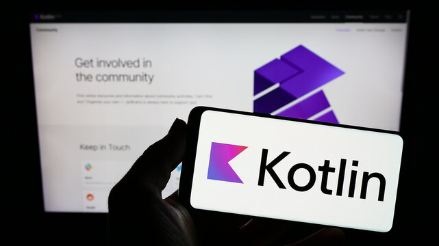 Stuttgart, Germany - 01-08-2023: Person holding smartphone with logo of programming language Kotlin on screen in front of website. Focus on phone display.