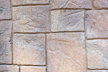 The stone wall is patterned in light brown tones, each cube is different, small and large alternately.