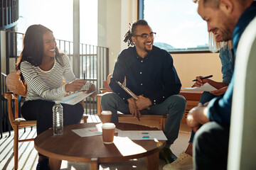 Diverse group of office colleagues laughing together during a meeting